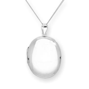 Puede incluir: Un colgante de plata con forma de relicario ovalado y pulido, sujeto a una fina cadena. El relicario tiene una superficie lisa y reflectante. La cadena es de diseño delicado. El fondo es blanco liso, resaltando el brillo del colgante.