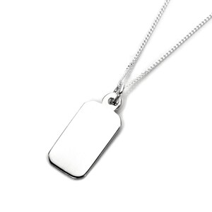 Pode incluir: Um colar com pingente retangular prateado e corrente fina. O pingente liso e refletivo pende de uma corrente delicada. O colar é exibido em um fundo branco, destacando seu design minimalista.