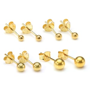 May include: Six pairs of gold-colored ball stud earrings. Each earring features a small, round ball at the end of a post, with a butterfly backing. The earrings are displayed on a white background.