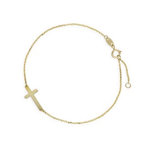 May include: A delicate gold bracelet with a sideways cross pendant. The bracelet has a fine chain and an adjustable clasp. The cross is a simple, elegant design. The jewelry is set against a white background.