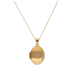 May include: A gold-colored oval locket pendant necklace. The locket has a small diamond-like accent in the center. The chain and pendant are a matching gold color. The necklace is displayed against a white background.