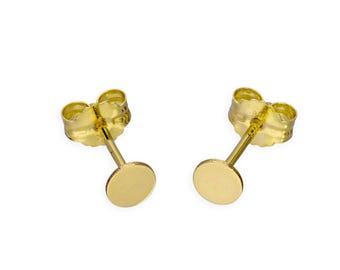 May include: A pair of gold-colored stud earrings. Each earring features a small, flat, circular disc attached to a post with a butterfly backing. The earrings are displayed against a white background.