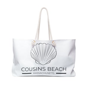 Op de afbeelding: Witte draagtas met crèmekleurige touwhandvatten. De tas heeft een grote zwarte schelpgrafiek en de woorden "COUSINS BEACH MASSACHUSETTS" in zwarte tekst. Een stijlvolle strandtas.