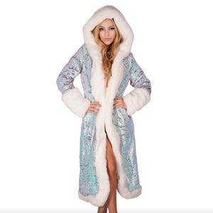 May include: A long, hooded coat with a light blue sequined exterior and white faux fur trim. The coat features a large hood and cuffs, with a flowing, open front design. The coat is designed to be worn as outerwear.