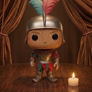 May include: A collectible figure of a character with a wooden texture, wearing a silver helmet and armor with red, green, and gold accents. The figure has black eyes and is adorned with two feathers. A lit white candle sits nearby on a wooden surface.