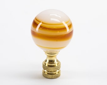 May include: A white and brown striped glass lamp finial with a gold metal base.