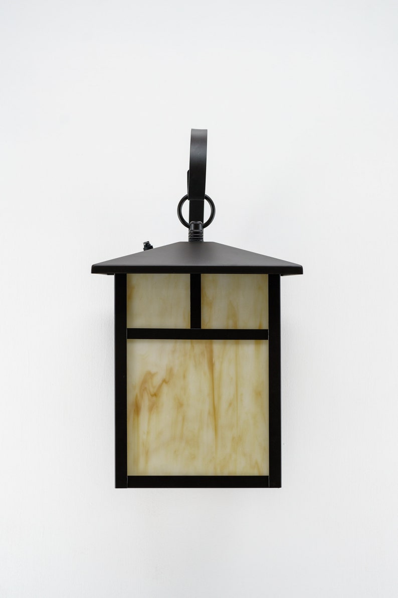 May include: Black outdoor wall light fixture with a rectangular glass shade and a decorative ring on the top.