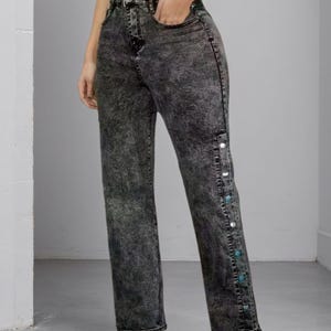 May include: A white ceramic mug with a black handle and the text "But First, Coffee" in a bold, black font. The mug is set against a blurred background, suggesting a cozy setting.