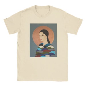 Peut inclure: Un t-shirt avec une peinture d'une femme aux cheveux foncés portant un châle à motifs colorés. La femme regarde sur le côté et a une auréole de lumière derrière sa tête.