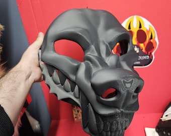 Könnte beinhalten: Eine mattschwarze, dreidimensionale Tiermaske mit einem stilisierten Wolfs- oder Hunde-Design. Die Maske hat markante, scharfe Zähne, eine definierte Schnauze und große Augenöffnungen. Die Oberfläche zeigt durchgehend sichtbare 3D-Druckschichten.