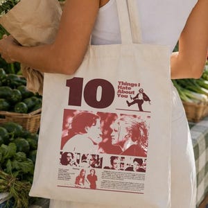 May include: A cream-colored canvas tote bag featuring a dark red graphic print. The design includes the large text 10 Things I Hate About You, a silhouette of a person, and several film still images from the movie, along with small printed text.