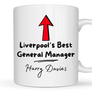 May include: White ceramic mug with a red arrow pointing upwards and the text "Liverpool's Best General Manager Harry Davies".