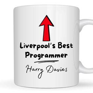 May include: White ceramic mug with a red arrow pointing upwards and the text "Liverpool's Best Programmer" with a line underneath. The name "Harry Davies" is written below the line.