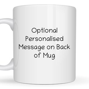 May include: A white ceramic mug featuring the black printed text Optional Personalized Message on Back of Mug centered on the front surface. The mug has a standard cylindrical body and a curved handle on the left side for holding the vessel.