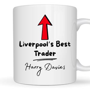 Peut inclure: Mug en céramique blanche avec le texte "Liverpool's Best Trader" et une flèche rouge pointant vers le haut. En dessous, le nom "Harry Davies" en cursive. La tasse a une anse blanche.