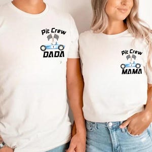 Op de afbeelding: Twee witte T-shirts met een blauwe racewagen afbeelding en de tekst "Pit Crew" op elk shirt. Het shirt aan de linkerkant zegt "Dada" en het shirt aan de rechterkant zegt "Mama".
