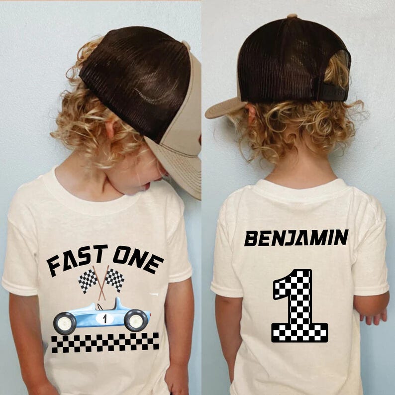 May include: White t-shirt with a blue race car and the text "FAST ONE" on the front. The back of the shirt has the name "BENJAMIN" and the number "1" with a checkered flag design.
