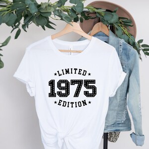 May include: White t-shirt with black text that reads "Limited Edition 1975".