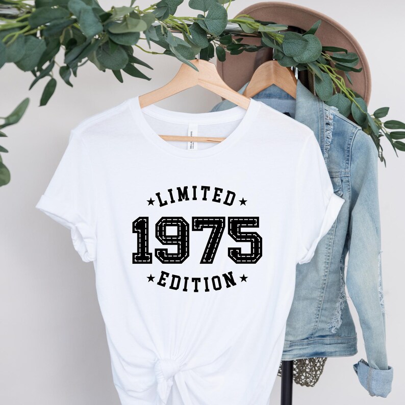 May include: White t-shirt with black text that reads "Limited Edition 1975".