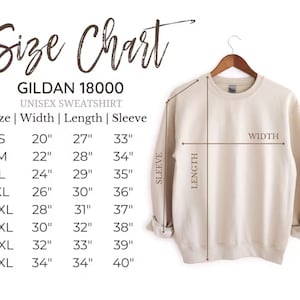 Op de afbeelding: Een beige Gildan 18000 unisex sweatshirt hangt aan een houten hanger. De afbeelding bevat een maattabel met afmetingen in cm voor breedte, lengte en mouwlengte, vari&euml;rend van maat S tot 4XL.