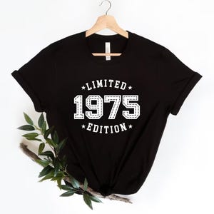 May include: Black t-shirt with white text that reads "*LIMITED* 1975 *EDITION*"