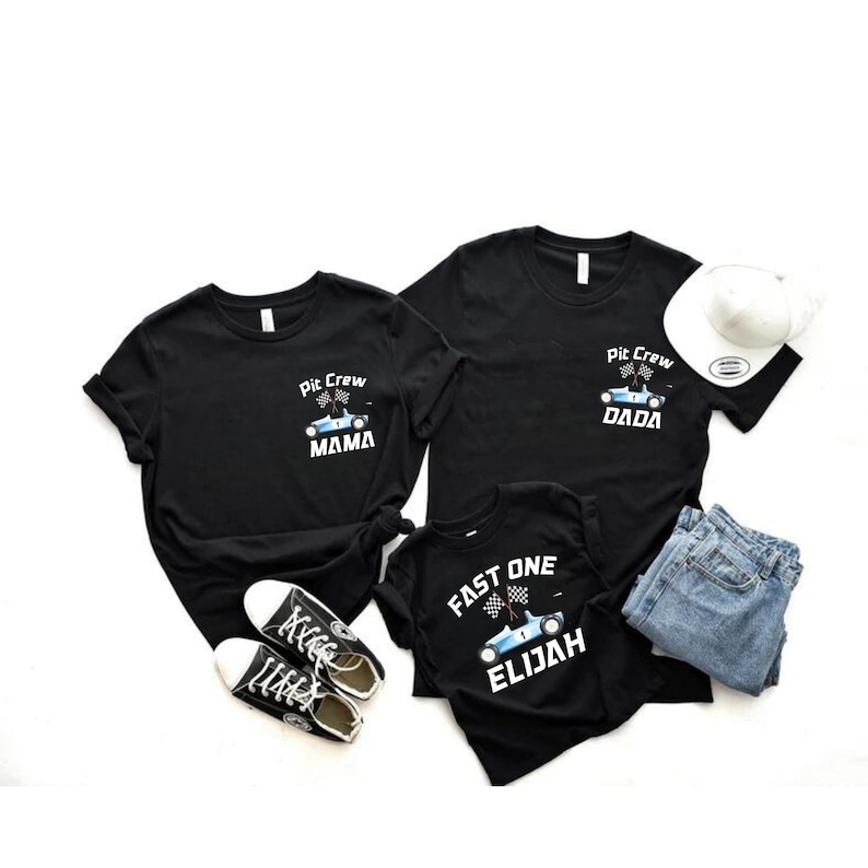 May include: Three black t-shirts with a racing car design. The shirts say "Pit Crew Mama", "Pit Crew Dada", and "Fast One Elijah".
