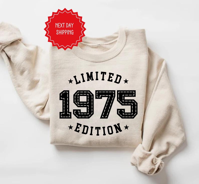 May include: A beige sweatshirt with black text that reads "Limited 1975 Edition" with stars on either side of the text.