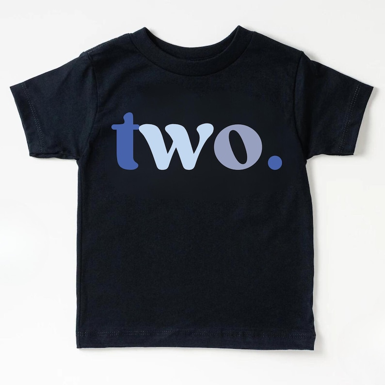 May include: Navy blue toddler t-shirt with the word "two" in shades of blue. The word is centered on the shirt, with the "t" in a darker blue, the "wo" in a lighter blue, and a blue dot at the end.