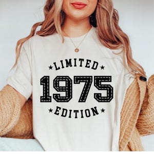 May include: White t-shirt with black text that reads "Limited 1975 Edition".