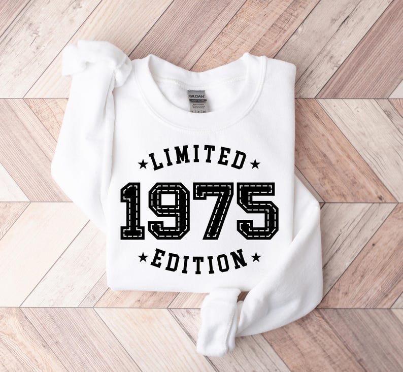 May include: White sweatshirt with black text that reads "*LIMITED* 1975 *EDITION*" with stars on either side of the text.
