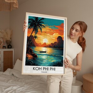 May include: A framed print depicting a sunset over a tropical island with a longtail boat in the water. The print is titled "Koh Phi Phi, Thailand".