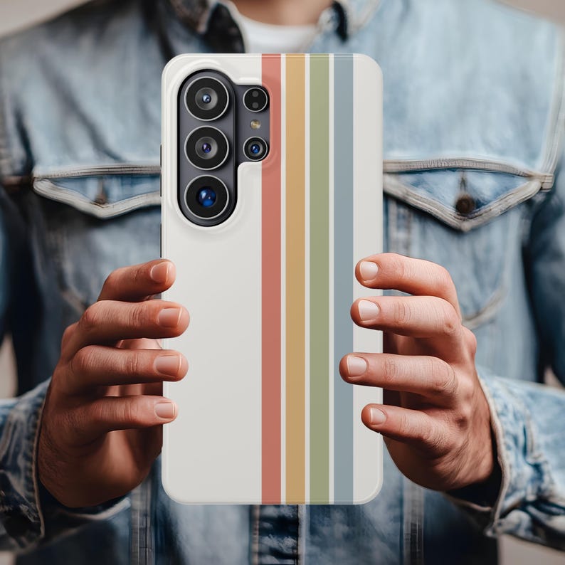 May include: A white phone case with a retro rainbow stripe design. The case features vertical stripes in red, orange, yellow, green, and blue. The phone case has a camera module with multiple lenses.