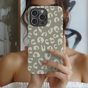 May include: A green and white phone case with a leopard print design. The case has a cutout for the camera lens.