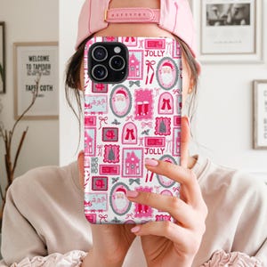 May include: A phone case with a festive Christmas pattern. The design features pink and white postage stamp-style illustrations of Santa Claus, houses, bows, and the word "JOLLY". The case has a glossy finish.