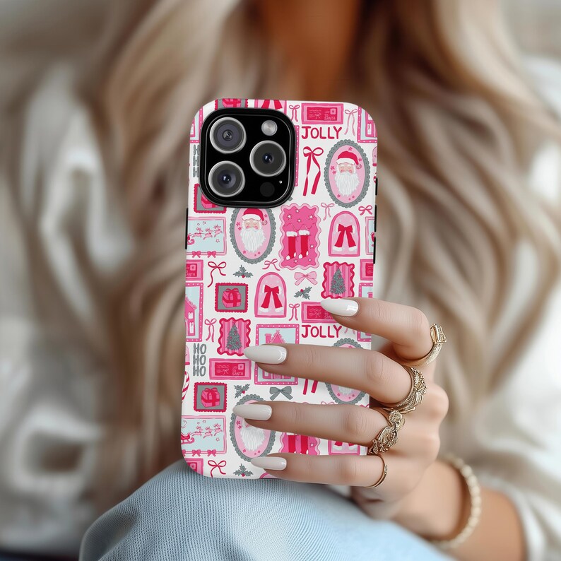 May include: A white iPhone case with a repeating pattern of pink and red Christmas-themed illustrations, including Santa Claus, bows, and the word "JOLLY". The case is held in a person's hand.