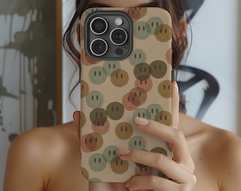 May include: A beige phone case with a pattern of colourful smiley faces. The case is designed for an iPhone with a triple lens camera.