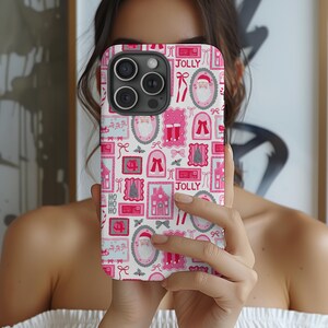May include: A pink and white phone case with a repeating Christmas-themed pattern. The design includes images of Santa Claus, Christmas trees, houses, bows, and the word "JOLLY". The case has a glossy finish.