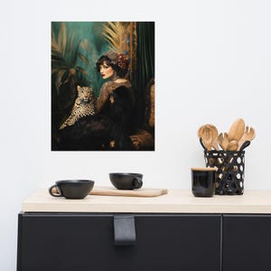 May include: A woman in a black dress and a red flower in her hair sits with a leopard in a lush green jungle setting.