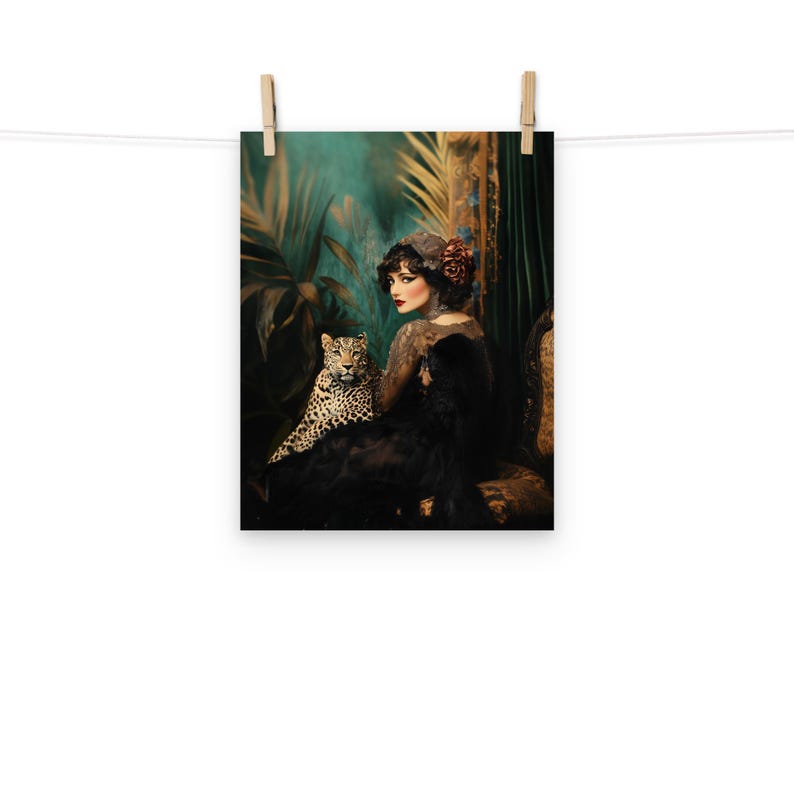 May include: A woman in a black dress and a red flower in her hair sits with a leopard in a lush green jungle setting.