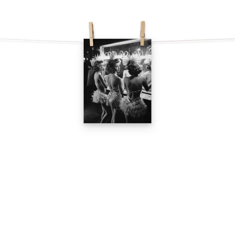May include: Three women in feathered costumes stand in front of a mirror, looking at their reflections. They are wearing sequined dresses and have their hair styled in updos.