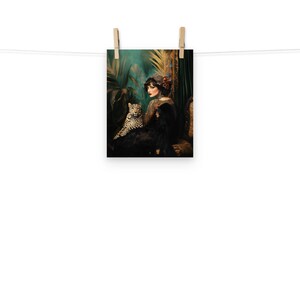 May include: A woman in a black dress and a red flower in her hair sits with a leopard in a lush green jungle setting.