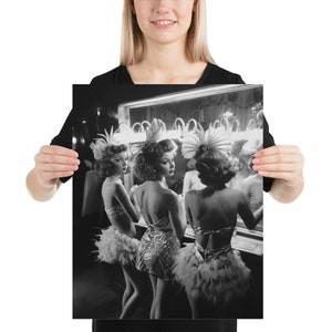 May include: Three women in vintage showgirl costumes stand in front of a mirror, adjusting their feathered headpieces. The women are wearing sequined and feathered costumes, and their reflections are visible in the mirror.