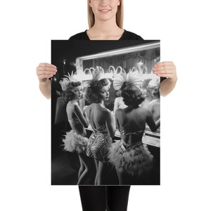 May include: Three women in black and white, wearing feathered headdresses and sequined costumes, stand in front of a mirror in a dressing room.