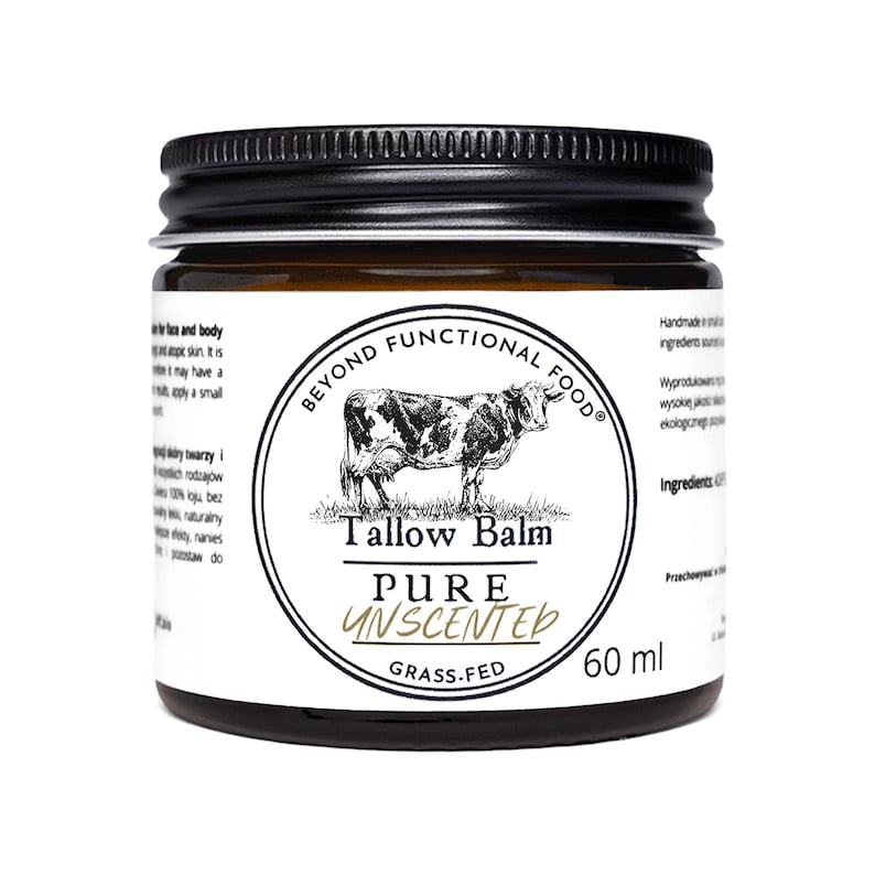 May include: A 60 ml amber glass jar with a black screw-top lid, featuring a white label with a black cow illustration. The text reads Beyond Functional Food, Tallow Balm, Pure Unscented, and Grass-Fed, with additional small text on the sides.