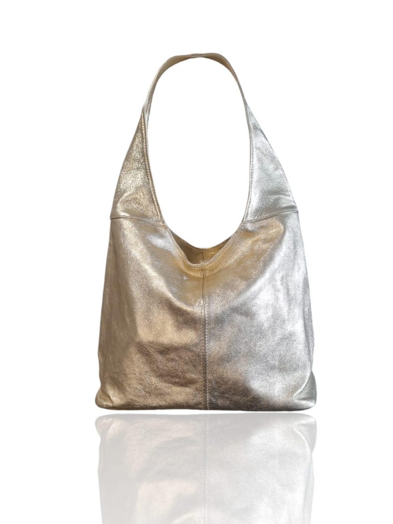 Puede incluir: Un bolso hobo de cuero plateado con una sola correa. El bolso tiene un aspecto informal y holgado.