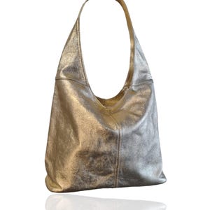 Puede incluir: Un bolso hobo de cuero met&aacute;lico plateado con una sola correa. El bolso tiene un aspecto informal y holgado.