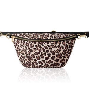 May include: A black and brown leopard print fanny pack with a gold zipper and black strap.