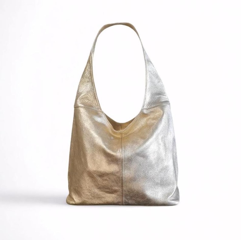 Puede incluir: Un bolso tote de cuero dorado y plateado con una sola correa.