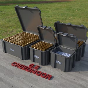 Peut inclure: Plusieurs conteneurs de stockage gris, certains ouverts, remplis de munitions de couleur laiton. Les conteneurs sont étiquetés "65cr". Le mot "CREEDMOOR" est épelé en lettres rouges sur la surface.