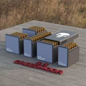 May include: Five gray ammo boxes with a skull graphic on the top box. Each box is filled with gold-colored bullets and labeled "65cr". The boxes are arranged in a pyramid shape with the skull box on top. The words "6.5 Creedmoor" are written in red letters on the wooden surface below the boxes.